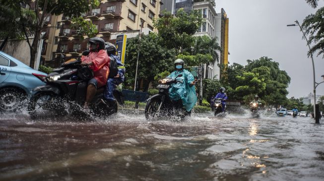 Kendaran melintasi genangan banjir di Jalan Cikini Raya, Jakarta, Selasa (18/1/2022).  ANTARA FOTO/Aprillio Akbar