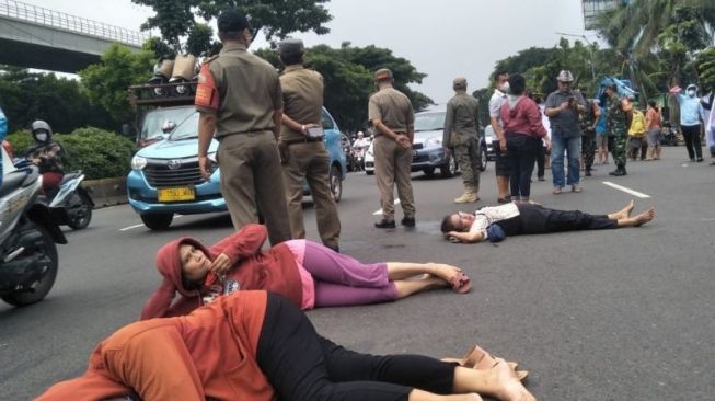 Demo Tiduran di Jalan, PKL RS UKI Cawang Tolak Relokasi Pemkot Jaktim: Di Sana Cuma Genderuwo yang Beli!