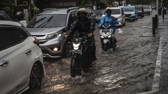 Kendaran melintasi genangan banjir di Jalan Cikini Raya, Jakarta, Selasa (18/1/2022).  ANTARA FOTO/Aprillio Akbar