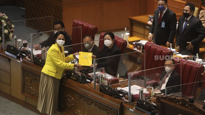 Juru Bicara Golkar Christina Aryani (kiri) memberikan laporan tanggapan fraksi kepada Ketua DPR RI Puan Maharani (kedua kanan) saat Rapat Paripurna DPR ke-13 Masa Persidangan III Tahun 2021-2022 di Kompleks Parlemen, Senayan, Jakarta, Selasa, (18/1/2022). [Suara.com/Angga Budhiyanto]