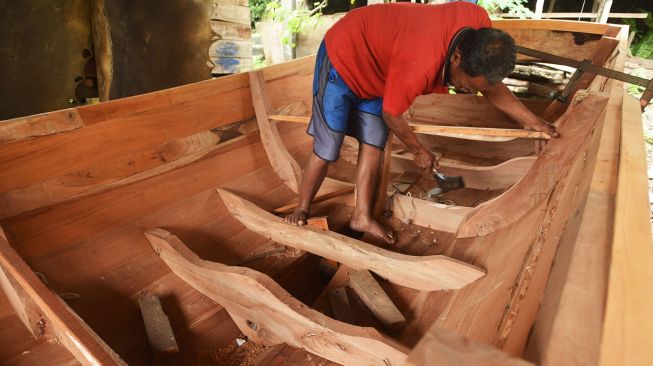 Pekerja menyelesaikan pembuatan perahu tradisional di Kampung Kendang, Margaluyu, Serang, Banten, Selasa (18/1/2022).  ANTARA FOTO/Asep Fathulrahman