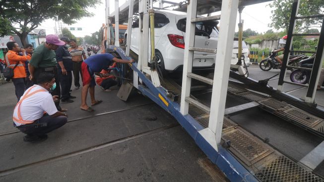 Petugas mengevakuasi truk yang tersangkut perlintasan kereta api di Kelurahan Balowerti, Kota Kediri, Jawa Timur, Selasa (18/1/2022).  ANTARA FOTO/Prasetia Fauzani