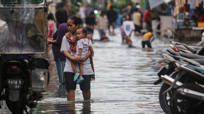 Seorang warga berjalan di tengah banjir di kawasan Cengkareng, Jakarta, Selasa (18/1/2022). Banjir tersebut terjadi karena buruknya drainase di kawasan itu serta tingginya instensitas hujan pada Selasa (18/1) siang. [ANTARA FOTO/Fauzan].