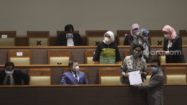 Ketua Pansus IKN Ahmad Doli Kurnia (kanan) memberikan dokumen hasil sidang Pansus Rancangan Undang-Undang Ibu Kota Negara (RUU IKN) kepada Menteri Keungan Sri Mulyani (kedua kanan) yang juga dihadiri Menteri Perencanaan Pembangunan Nasional (PPN)/Kepala Badan Perencanaan Pembangunan Nasional (Bappenas) Suharso Monoarfa (kiri) pada Rapat Paripurna ke-13 DPR RI Masa Persidangan III Tahun Sidang 2021-2022 yang beragendakan Pembicaraan Tingkat II/Pengambilan Keputusan atas RUU tentang Ibu Kota Negara di Kompleks Parlemen, Jakarta, Selasa (18/1/2022). [Suara.com/Angga Budhiyanto]