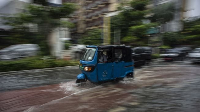 Kendaran melintasi genangan banjir di Jalan Cikini Raya, Jakarta, Selasa (18/1/2022).  ANTARA FOTO/Aprillio Akbar