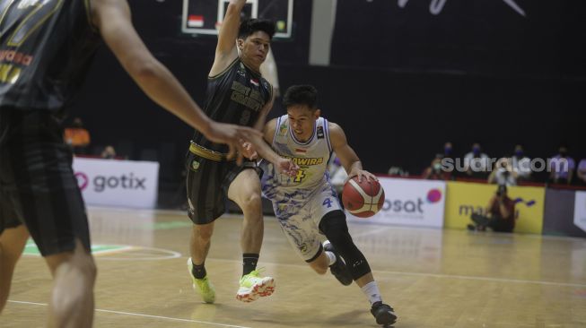 Pebasket Prawira Bandung Abraham Damar Grahita (kanan) berusaha melewati pebasket West Bandits Combiphar Solo Rio Disi pada pertandingan Seri 1 Jakarta Indonesian Basketball League (IBL) 2022 di Hall Basket Senayan, GBK, Jakarta, Senin (17/1/2022). [Suara.com/Angga Budhiyanto]