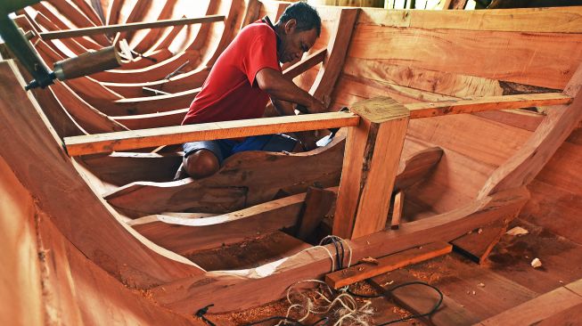 Pekerja menyelesaikan pembuatan perahu tradisional di Kampung Kendang, Margaluyu, Serang, Banten, Selasa (18/1/2022).  ANTARA FOTO/Asep Fathulrahman