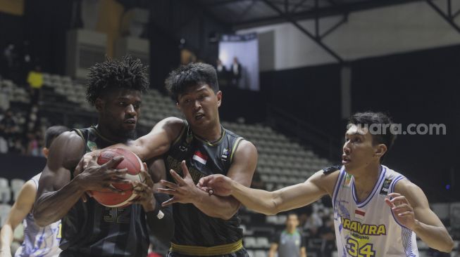 Pebasket West Bandits Combiphar Solo Dmonta Quoshawn Harris (kiri) dan Habib Tito Aji (tengah) mengamankan bola yang coba direbut oleh pebasket Prawira Bandung Pandu Wiguna pada pertandingan Seri 1 Jakarta Indonesian Basketball League (IBL) 2022 di Hall Basket Senayan, GBK, Jakarta, Senin (17/1/2022). [Suara.com/Angga Budhiyanto]