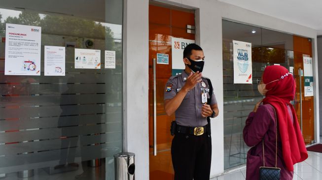 Satpam memberikan penjelasan kepada nasabah tentang penutupan sementara Kantor Cabang BNI 46 di Kota Madiun, Jawa Timur, Rabu (19/1/2022). ANTARA FOTO/Siswowidodo
