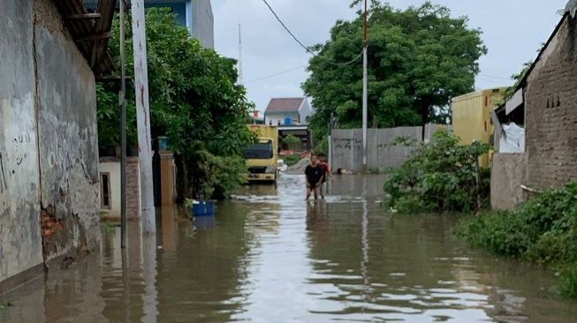 Dua anak melintas di tengah banjir di kawasan Benda, Kota Tangerang, Rabu (19/1/2022). [Ist]