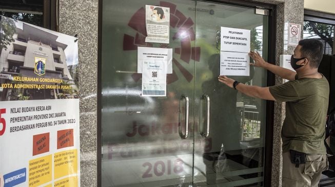 Petugas memasang informasi masyarakat di Kantor Kelurahan Gondangdia, Jakarta, Rabu (19/1/2022).  ANTARA FOTO/Muhammad Adimaja