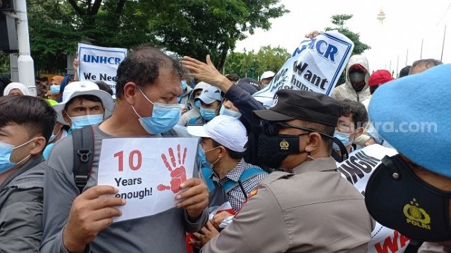 Pengungsi Afghanistan terlibat adu dorong dengan polisi saat berujuk rasa di Lapangan IRTI Monas, Jakarta Pusat. (Suara.com/Yaumal)
