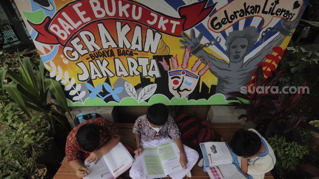 Anak-anak membaca buku di pustaka mini Bale Buku di Kelurahan Dukuh, Kramat Jati, Jakarta, Kamis (20/1/2022). [Suara.com/Angga Budhiyanto]