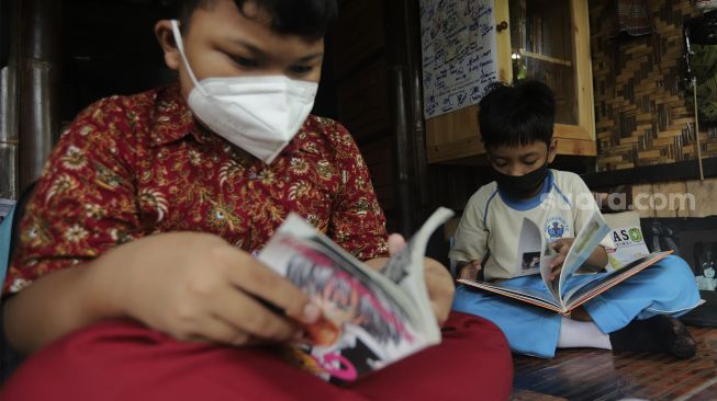 Anak-anak membaca buku di pustaka mini Bale Buku di Kelurahan Dukuh, Kramat Jati, Jakarta, Kamis (20/1/2022). [Suara.com/Angga Budhiyanto]