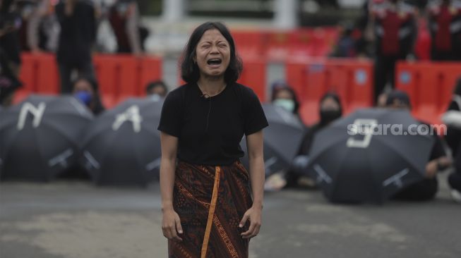 Massa yang tergabung dalam Jaringan Solidaritas Korban untuk Keadilan (JSKK) melakukan aksi teatrikal selama aksi Kamisan Ke-714 di seberang Istana Merdeka, Jakarta, Kamis (20/1/2022). [Suara.com/Angga Budhiyanto]