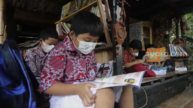 Anak-anak membaca buku di pustaka mini Bale Buku di Kelurahan Dukuh, Kramat Jati, Jakarta, Kamis (20/1/2022). [Suara.com/Angga Budhiyanto]