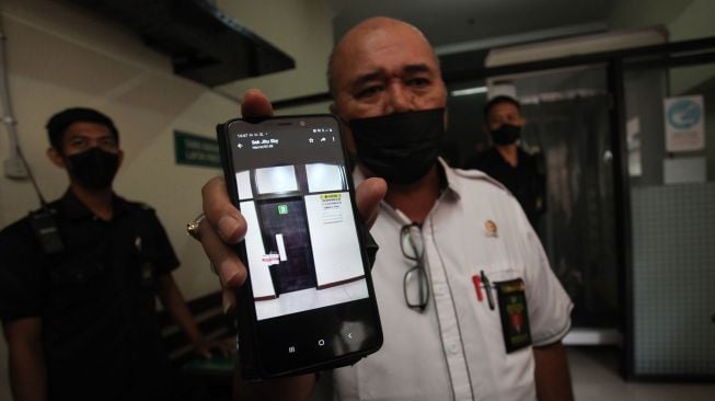 Humas Pengadilan Negeri (PN) Surabaya Martin Ginting (kanan) menunjukkan foto ruangan hakim yang disegel oleh Komisi Pemberantasan Korupsi di Pengadilan Negeri Surabaya, Surabaya, Jawa Timur, Kamis (20/1/2022).  ANTARA FOTO/Didik Suhartono