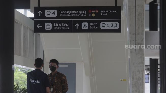 Petugas berdiri di bawah papan petunjuk arah atau 'wayfinding' di Halte Integrasi CSW, Kebayoran Baru, Jakarta, Jumat (21/1/2022). [Suara.com/Angga Budhiyanto]