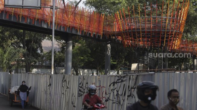 Sejumlah kendaraan melintas di bawah jembatan penghubung taman selatan dan utara pada revitalisasi Taman Tebet menjadi Tebet Eco Garden di Jalan Tebet Timur Raya, Jakarta, Jumat (21/1/2022). [Suara.com/Angga Budhiyanto]