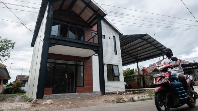 Warga melintas di depan rumah tahan gempa di Rangkasbitung, Lebak, Banten, Jumat (21/1/2022).  ANTARA FOTO/Muhammad Bagus Khoirunas