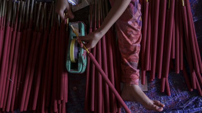 Seorang pekerja membungkus hio di Kosambi, Kabupaten Tangerang, Banten, Jumat (21/1/2022). [ANTARA FOTO/Fauzan]