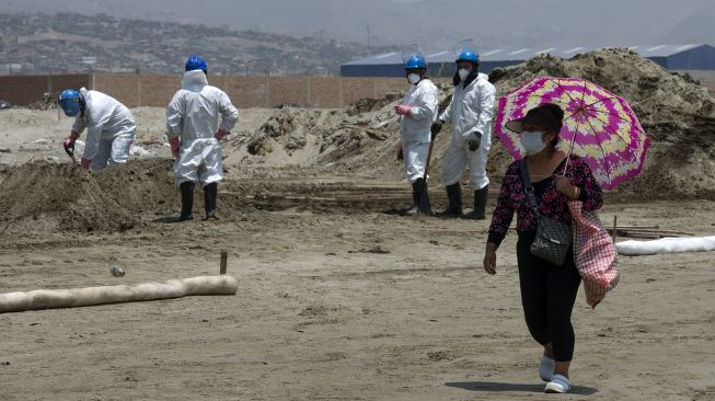 Seorang warga berjalan saat petugas membersihkan tumpahan minyak dari pantai di Provinsi Callao, Peru, pada (17/1/2022). [CRIS BOURONCLE / AFP]