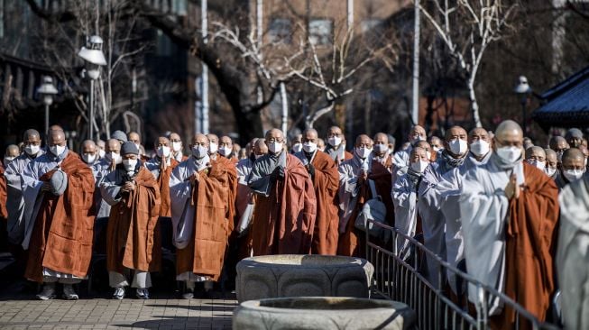 Anggota Ordo Jogye, sekte Buddha terbesar di Korea Selatan, berdoa saat mengadakan rapat umum di Kuil Jogye, Seoul, Jumat (21/1/2022). [ANTHONY WALLACE / AFP]