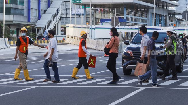 Warga menyeberang melalui pelican crossing di Kawasan Glodok, Jakarta Barat, Minggu (23/1/2022). [Suara.com/Alfian Winanto]