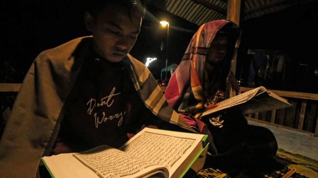 Warga membaca Al-Quran dengan penerangan listrik program listrik masuk desa daerah tertinggal di Dusun Jabal Antara, Aceh Utara.