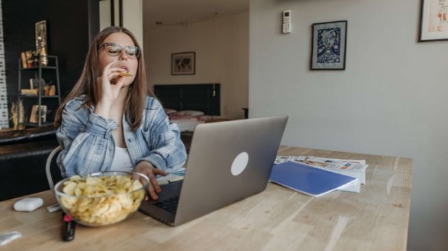 Ilustrasi wanita makan camilan.(Pexels/Pavel Danilyuk)