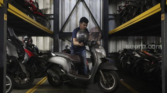 Pekerja menurunkan sepeda motor di Soul Parking, Kebon Kacang, Jakarta, Senin (24/1/2022). [Suara.com/Angga Budhiyanto]