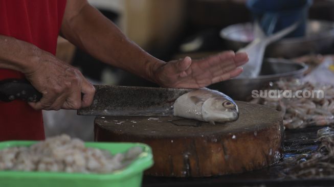 Pedagang memotong ikan bandeng pesanan pembeli di kawasan Petak Sembilan, Glodok, Jakarta, Senin (24/1/2022). [Suara.com/Angga Budhiyanto]