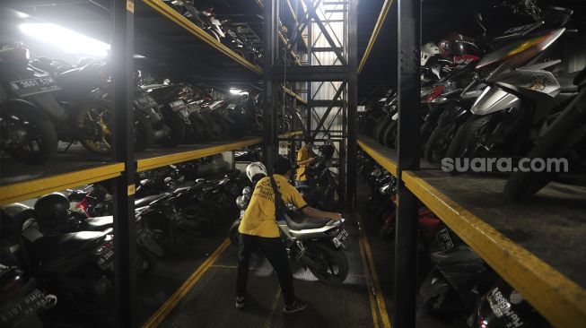 Pekerja menurunkan sepeda motor di Soul Parking, Kebon Kacang, Jakarta, Senin (24/1/2022). [Suara.com/Angga Budhiyanto]