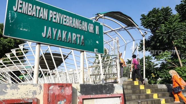 Sejumlah warga melintas di Jembatan Penyeberangan Orang (JPO) Jayakarta di Menteng, Jakarta Pusat, Senin (24/1/2022). [Suara.com/Alfian Winanto]