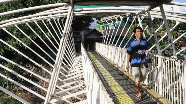 Warga melintas di Jembatan Penyeberangan Orang (JPO) Jayakarta di Menteng, Jakarta Pusat, Senin (24/1/2022). [Suara.com/Alfian Winanto]