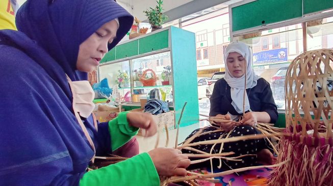 Para pengrajin kerajinan tangan berbahan dasar eceng gondok tengah menyelesaikan cover lampu (partahi/suara.com)