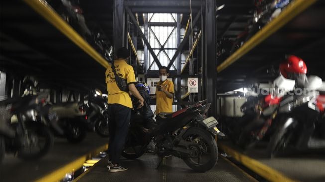 Pekerja menurunkan sepeda motor di Soul Parking, Kebon Kacang, Jakarta, Senin (24/1/2022). [Suara.com/Angga Budhiyanto]