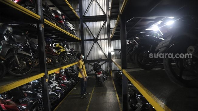 Pekerja menurunkan sepeda motor di Soul Parking, Kebon Kacang, Jakarta, Senin (24/1/2022). [Suara.com/Angga Budhiyanto]