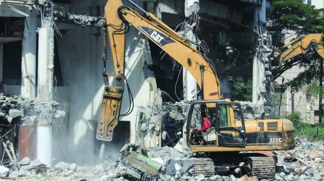 Alat berat meruntuhkan bangunan museum Telekomunikasi yang akan direnovasi di TMII, Jakarta, Senin (24/1/2022).  [Suara.com/Septian]