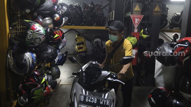 Pekerja mengeluarkan sepeda motor di Soul Parking, Kebon Kacang, Jakarta, Senin (24/1/2022). [Suara.com/Angga Budhiyanto]