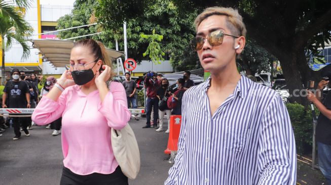 Artis Emma Waroka ditemani Kim Hawt saat datang untuk membuat laporan di Polda Metro Jaya, Jakarta Selatan, Senin (24/1/2022). [Suara.com/Alfian Winanto]