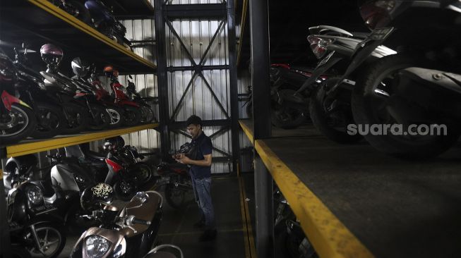 Pekerja menurunkan sepeda motor di Soul Parking, Kebon Kacang, Jakarta, Senin (24/1/2022). [Suara.com/Angga Budhiyanto]