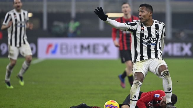 Bek Juventus Alex Sandro (kanan) bereaksi setelah menekel gelandang AC Milan Rade Krunic (Bawah) selama pertandingan sepak bola Serie A Italia antara AC Milan melawan  Juventus di Stadion San Siro, Senin (24/1/2022) dini hari WIB.  Alberto PIZZOLI / AFP

