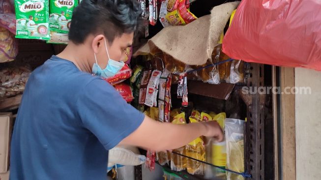 Salah satu pedagang di Pasar Modern Serpong Kota Tangerang Selatan menata minyak goreng kemasan di warungnya, Senin (25/1/2022). [SuaraJakarta.id/Wivy Hikmatullah]