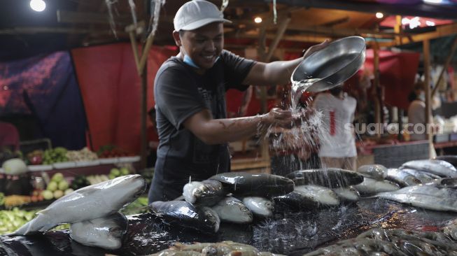 Pedagang membersihkan ikan bandeng di kawasan Petak Sembilan, Glodok, Jakarta, Senin (24/1/2022). [Suara.com/Angga Budhiyanto]