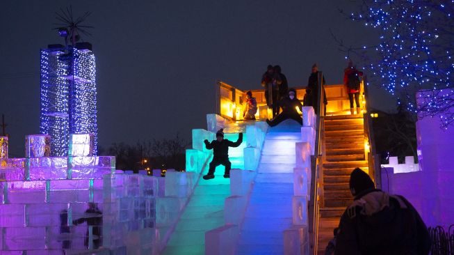 Anak-anak menikmati seluncuran di samping Ice Palace Maze, Stillwater, Minnesota, Amerika Serikat, pada (21/1/2022). [KEREM YUCEL / AFP]