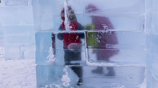 Pengunjung terlihat melalui dinding transparan di Ice Palace Maze, Stillwater, Minnesota, Amerika Serikat, pada (21/1/2022). [KEREM YUCEL / AFP]