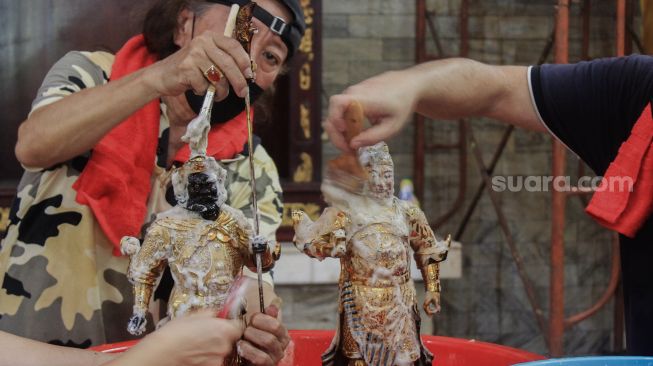 Petugas membersihkan patung di Vihara Amurva Bhumi, Jakarta, Selasa (25/1/2022). [Suara.com/Septian]