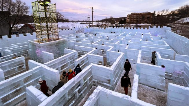 Pengunjung berjalan di Ice Palace Maze, Stillwater, Minnesota, Amerika Serikat, pada (21/1/2022). [KEREM YUCEL / AFP]