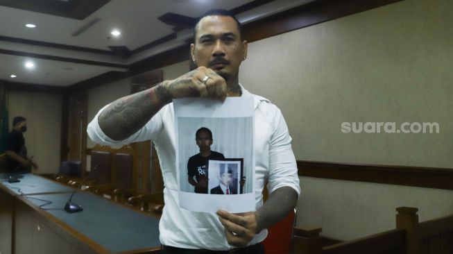 Musisi I Gede Ari Astina atau Jerinx SID menunjukkan bukti kepada awak media usai menjalani sidang lanjutan kasus pengancaman di Pengadilan Negeri Jakarta Pusat, Selasa (25/1/2022). [Suara.com/Alfian Winanto]